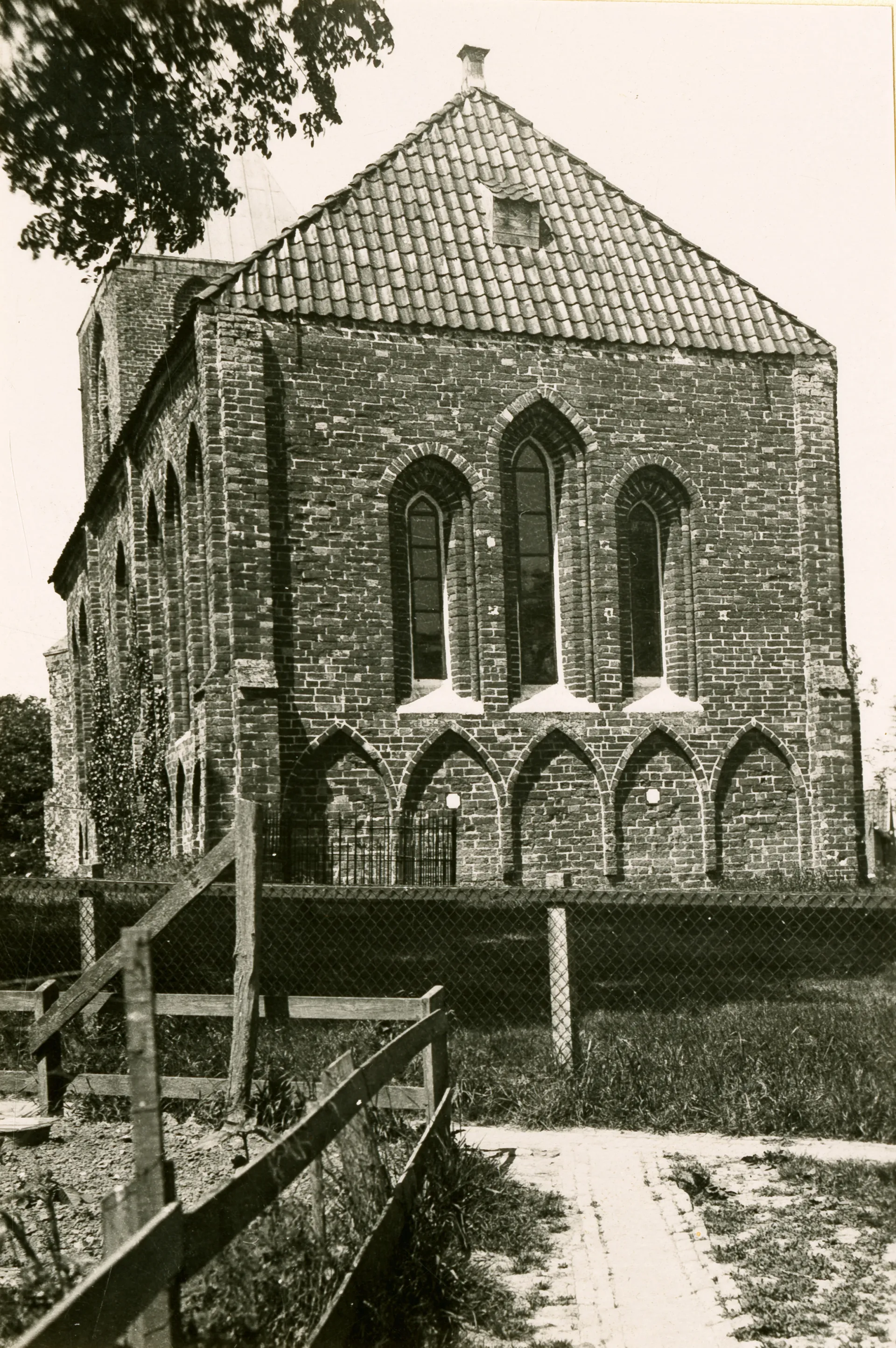 Foto van de achterkant van de Mariakerk in Krewerd. Een historische stenen kerk met hoge ramen.