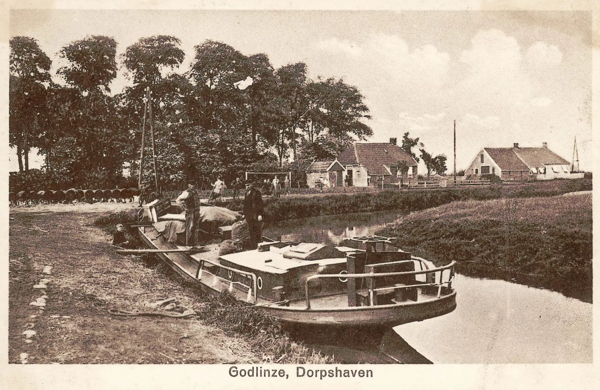 Boot afgemeerd in de dorpshaven van Godlinze met huisjes op de achtergrond.