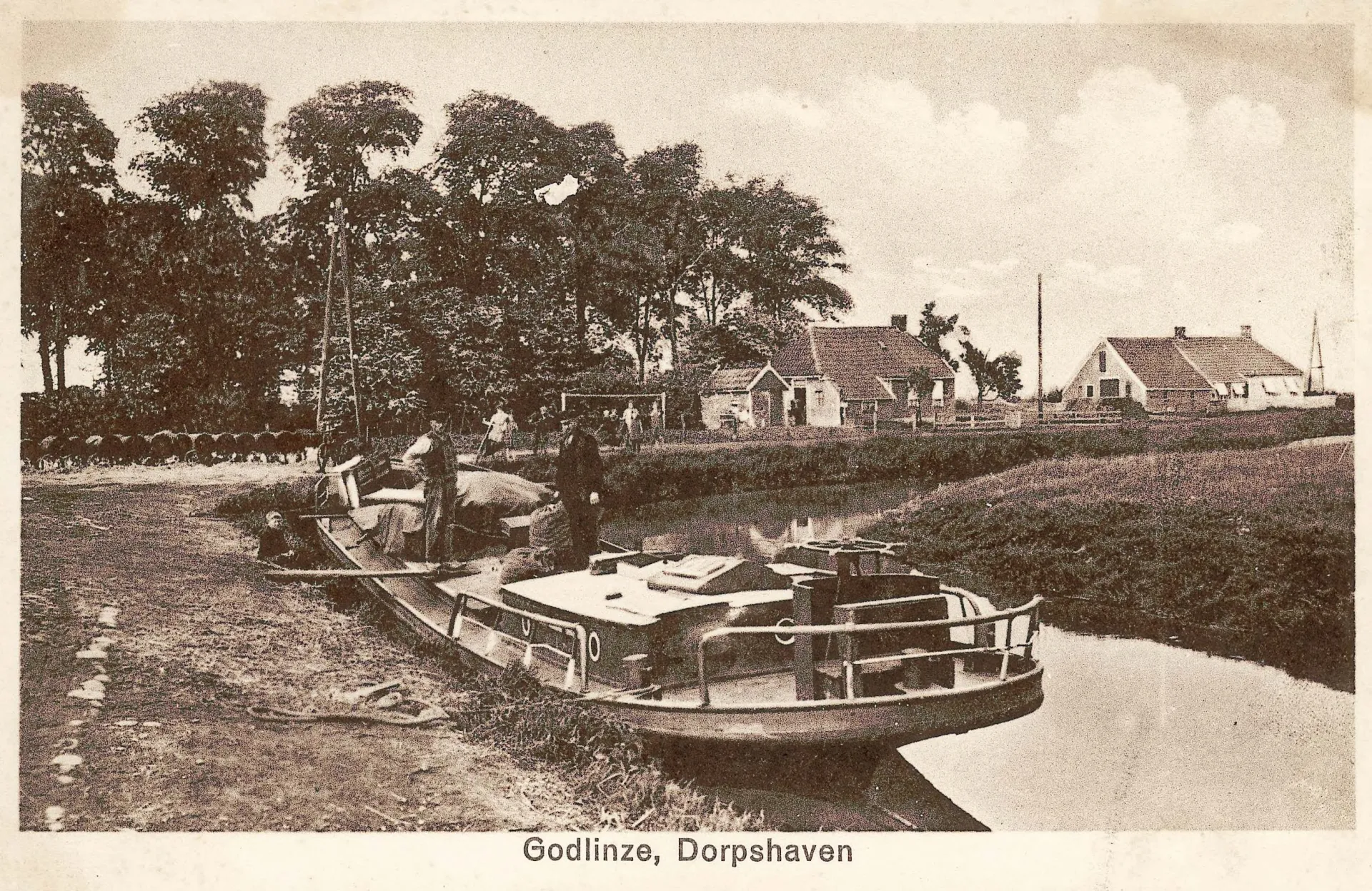 Boot afgemeerd in de dorpshaven van Godlinze met huisjes op de achtergrond.