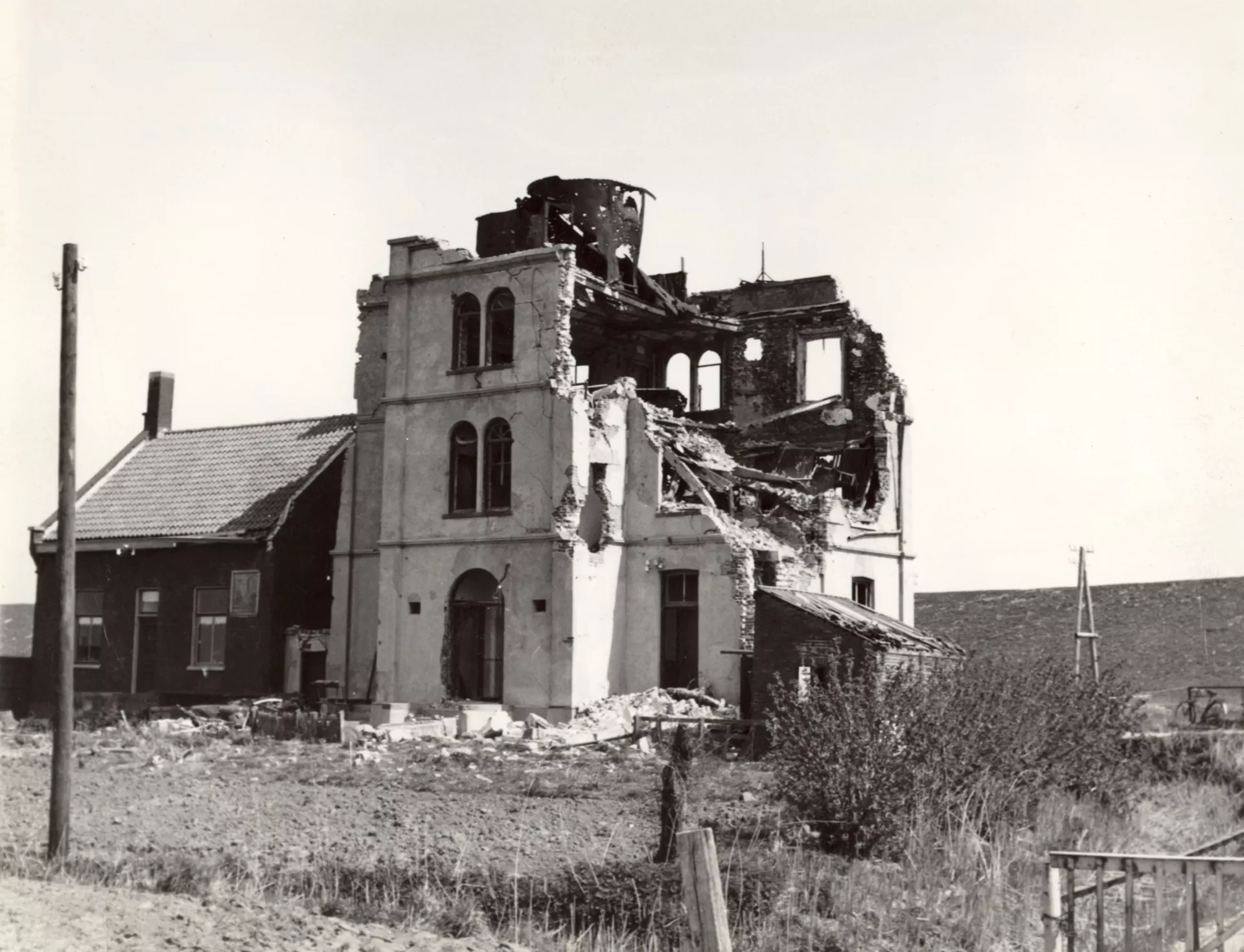 Restanten van de zwaar beschadigde vuurtoren van Uiteinde met het vuurtorenwachterswoning ernaast die nog intact is.