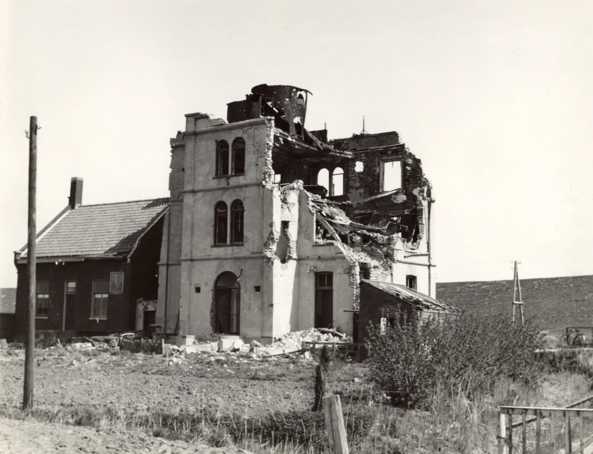 Restanten van de zwaar beschadigde vuurtoren van Uiteinde met het vuurtorenwachterswoning ernaast die nog intact is.