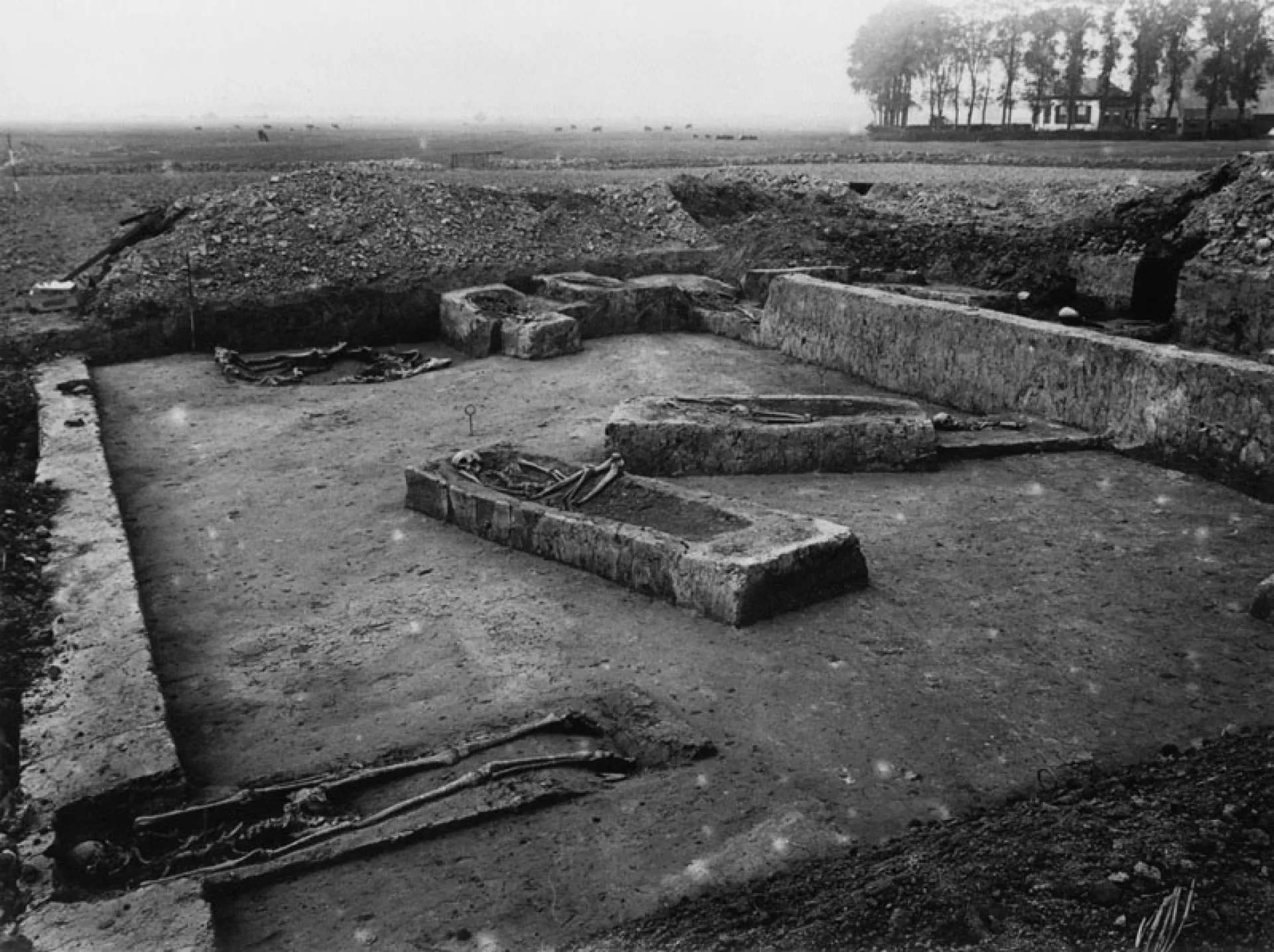Archeologische opgraving met oude graven in een open veld.