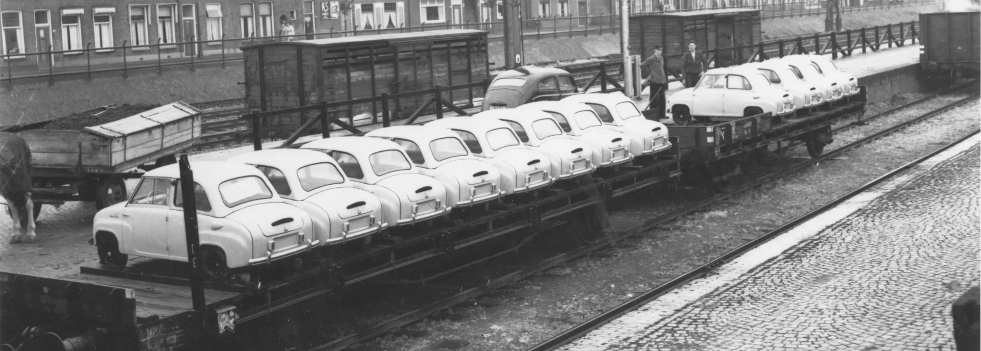 Oude zwart-witfoto van meerdere kleine auto's genaamd Goggomobils die op een treinwagon worden vervoerd voor importeur Gremi te Groningen.