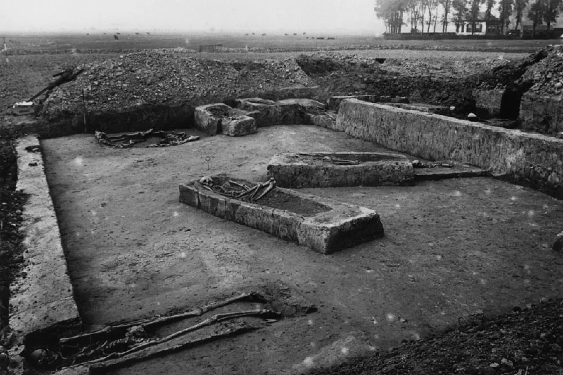 Archeologische opgraving met oude graven in een open veld.