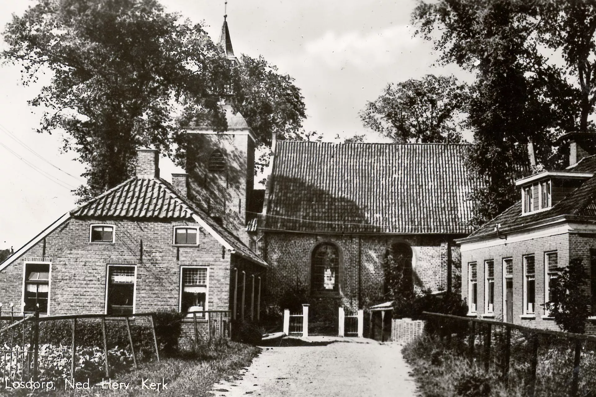 Foto van Losdorp na de Tweede Wereldoorlog met een kerk en omliggende gebouwen in een landelijke omgeving.