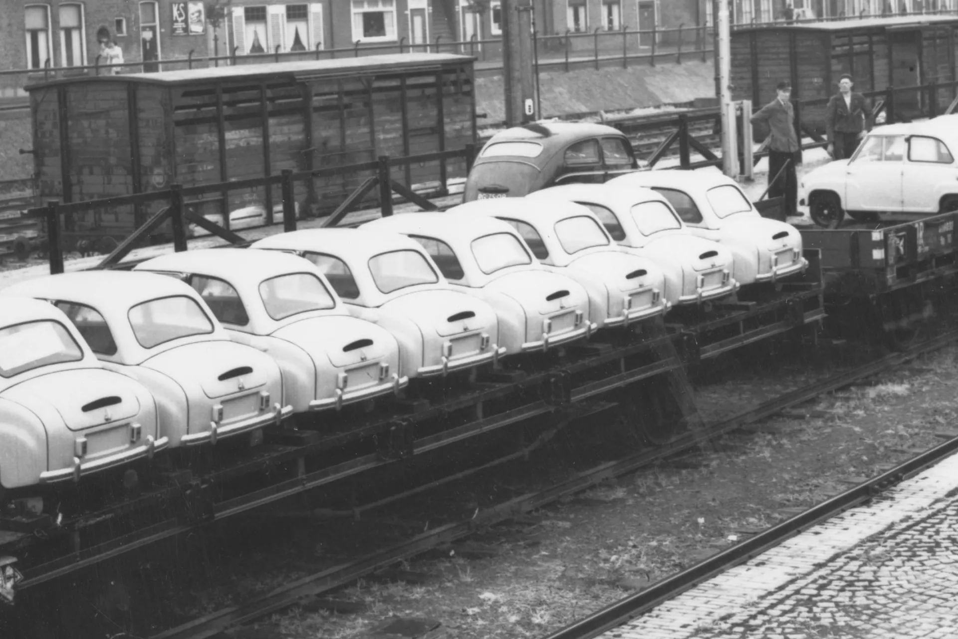 Oude zwart-witfoto van meerdere kleine auto's genaamd Goggomobils die op een treinwagon worden vervoerd voor importeur Gremi te Groningen.