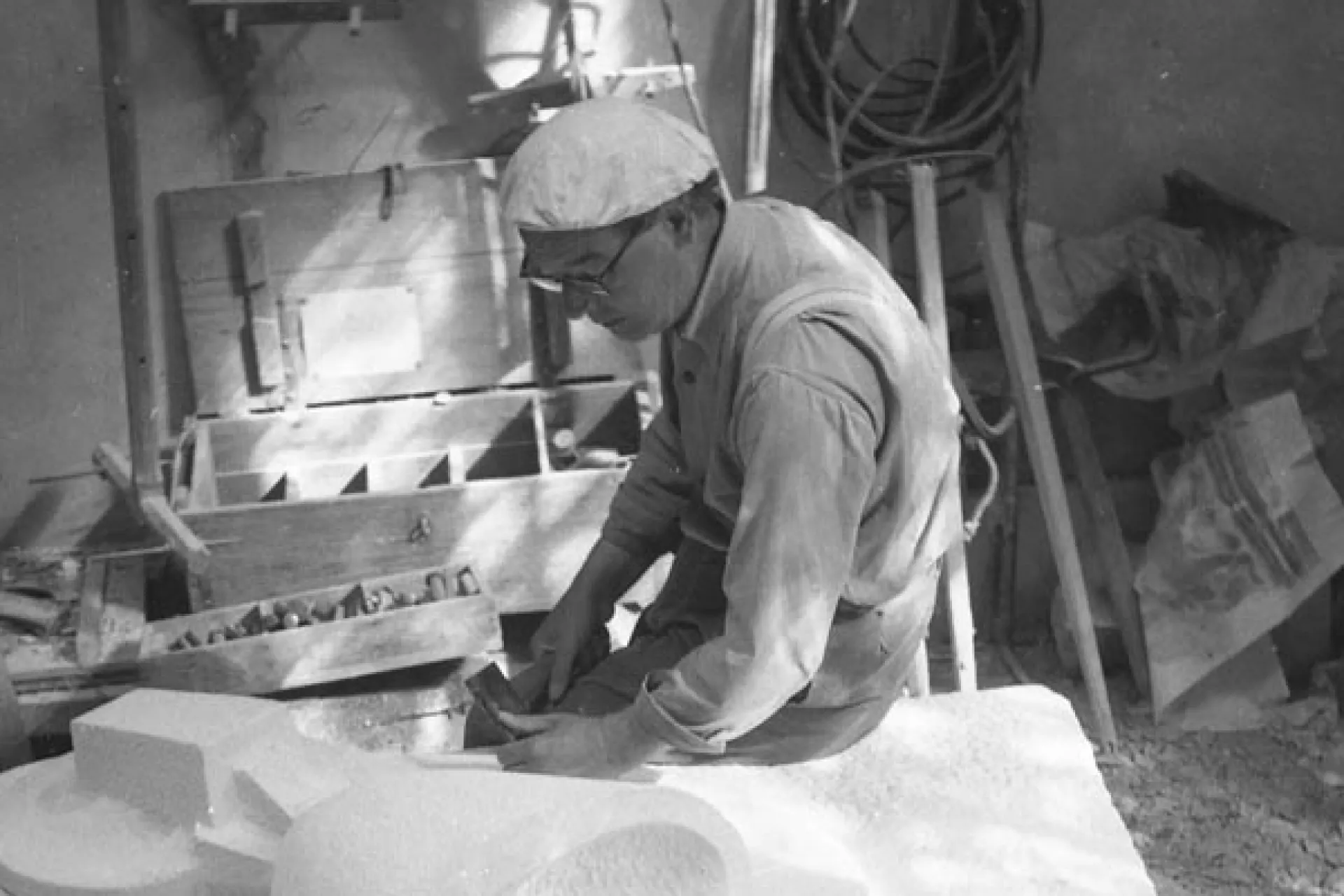 Een man is geconcentreerd aan het beeldhouwen in een atelier.