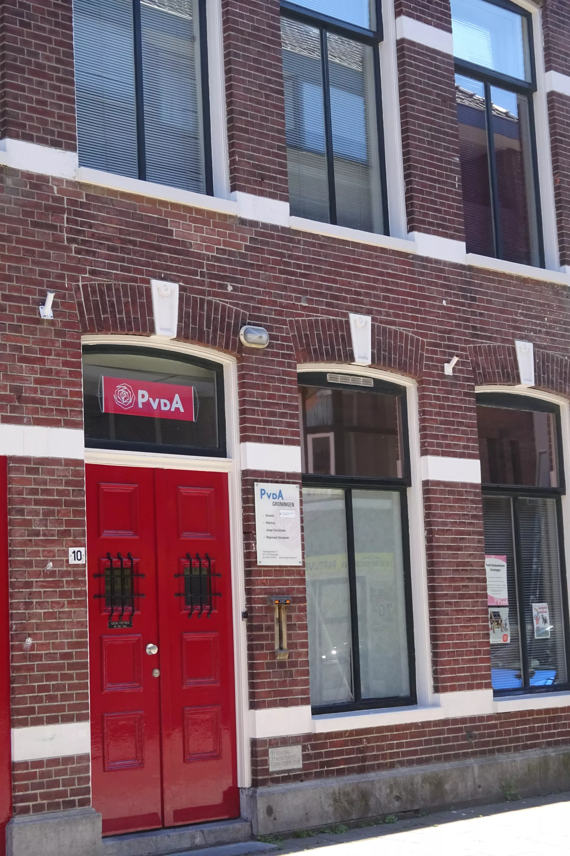 Gevel van een gebouw met rode deuren en een bord van "PvdA".